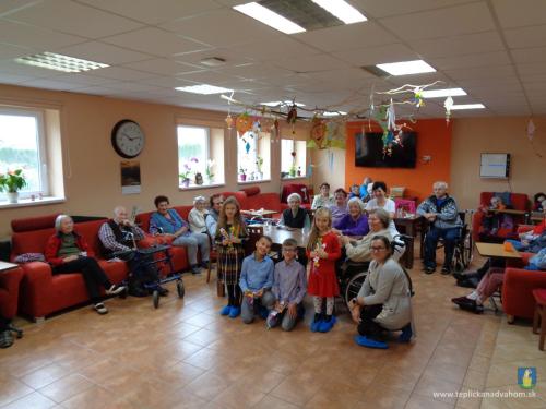 Spoločná fotografia detí zo Základnej školy s materskou školou a pani učiteľkou so seniormi z Domova